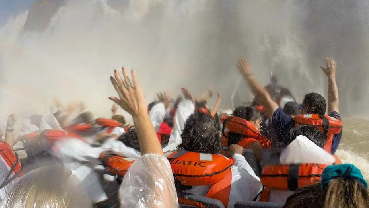 Tourists in orange life jackets on the Gran Aventura boat driving into spray on an Iguazu Falls boat tour, Argentina