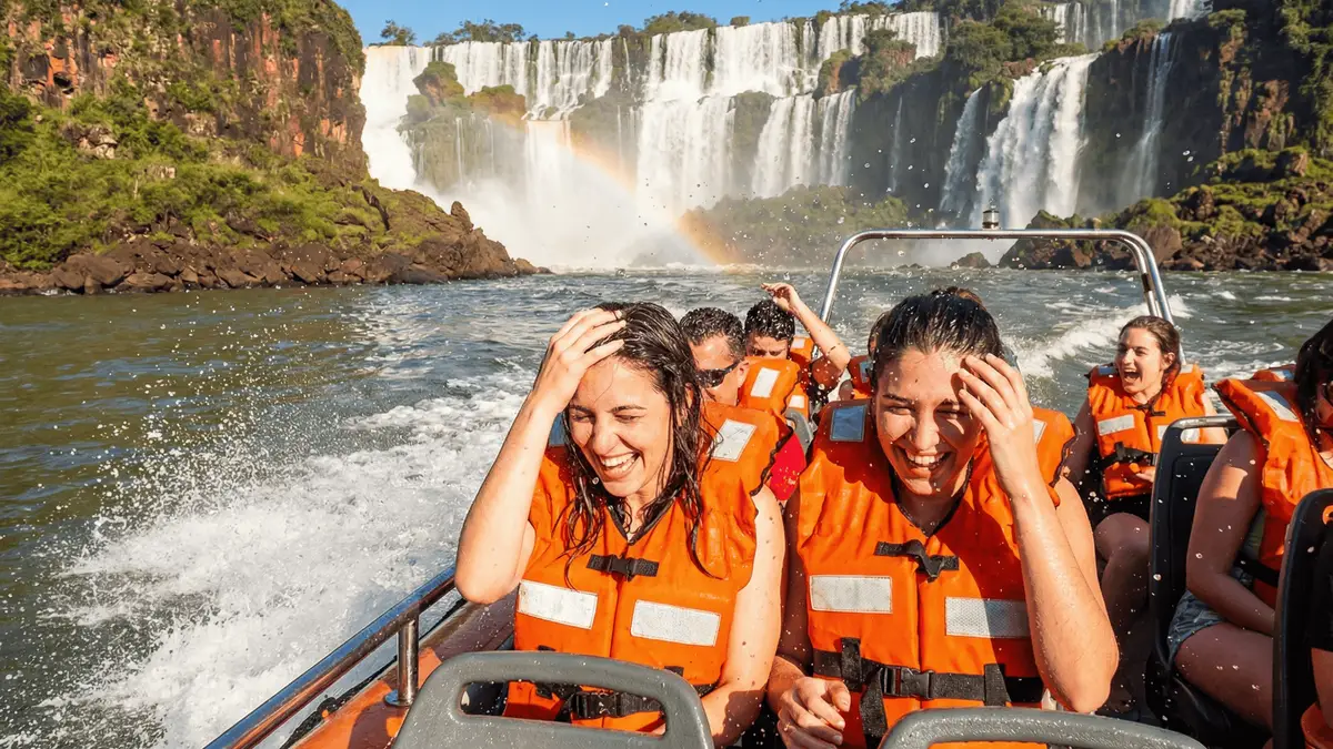 Boat crew and passengers below a curtain of falling water on a Great Adventure Iguazu Falls boat tour in Argentina